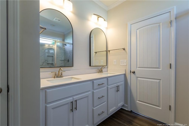 bathroom with hardwood / wood-style flooring, ornamental molding, a shower with shower door, and vanity