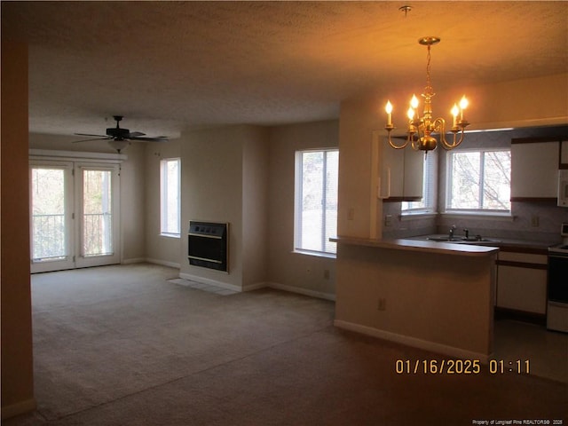 kitchen featuring electric stove, decorative light fixtures, carpet floors, heating unit, and ceiling fan with notable chandelier