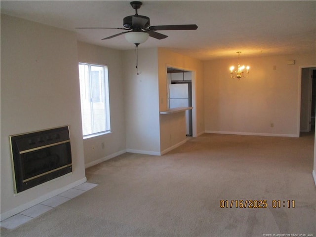 unfurnished living room with ceiling fan with notable chandelier and light colored carpet