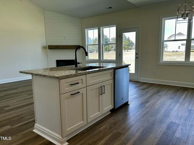 kitchen featuring light stone counters, stainless steel dishwasher, white cabinetry, a sink, and an island with sink