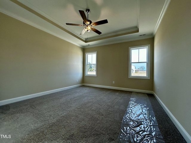 carpeted empty room featuring a raised ceiling, visible vents, ornamental molding, ceiling fan, and baseboards