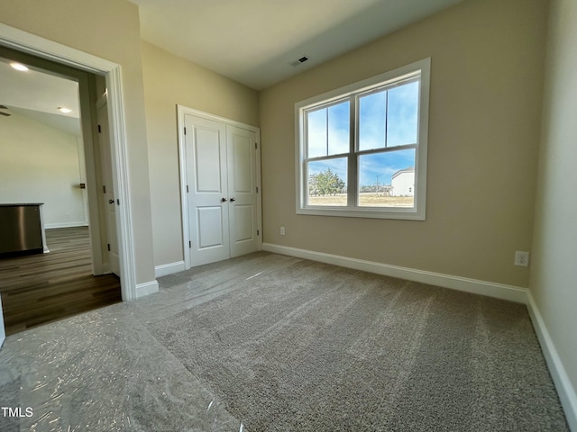 unfurnished bedroom with baseboards, a closet, visible vents, and carpet flooring