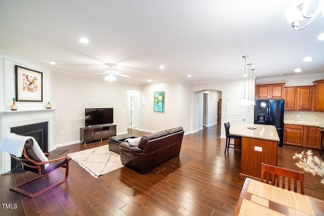 living room with dark hardwood / wood-style flooring, crown molding, and ceiling fan