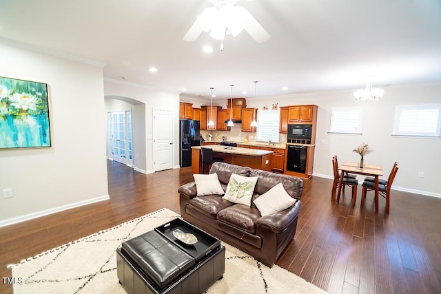 living room featuring crown molding, ceiling fan with notable chandelier, and dark hardwood / wood-style floors