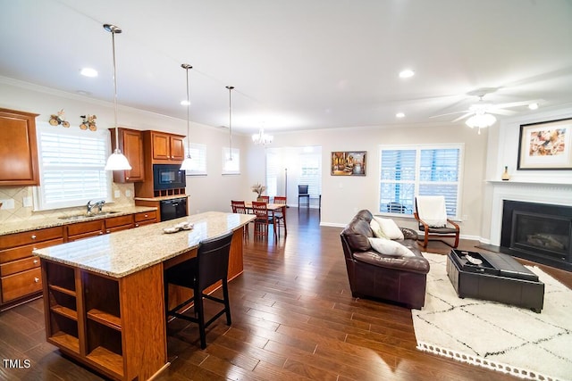 kitchen with pendant lighting, backsplash, a center island, black appliances, and ceiling fan with notable chandelier