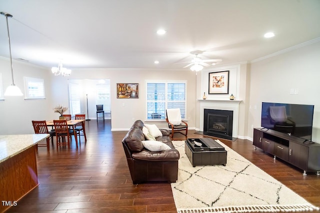 living room with crown molding, ceiling fan with notable chandelier, and dark hardwood / wood-style flooring