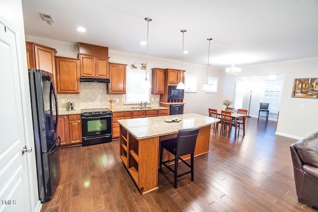 kitchen with decorative light fixtures, a kitchen bar, decorative backsplash, a center island, and black appliances