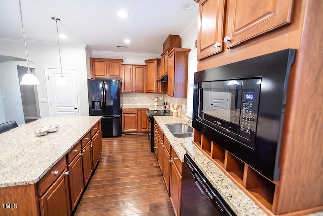 kitchen with crown molding, hanging light fixtures, black appliances, a kitchen island, and decorative backsplash