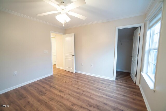 unfurnished bedroom with multiple windows, a walk in closet, a closet, and ceiling fan