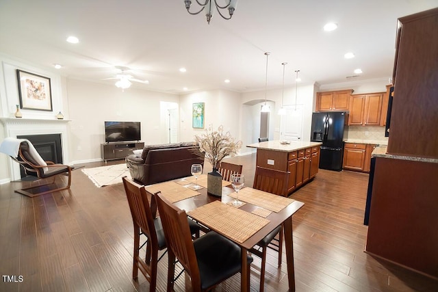 dining space featuring hardwood / wood-style flooring, crown molding, and ceiling fan with notable chandelier