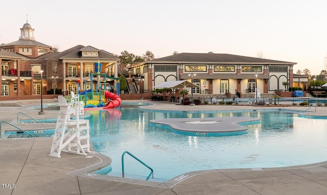 pool at dusk with a patio and a water slide