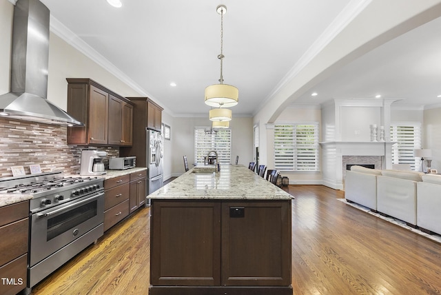 kitchen featuring backsplash, a kitchen island, crown molding, stainless steel appliances, and wall chimney exhaust hood