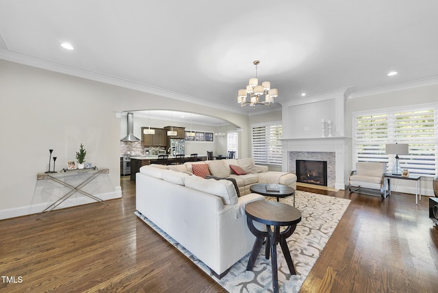 living room featuring crown molding, a fireplace, an inviting chandelier, and dark hardwood / wood-style floors