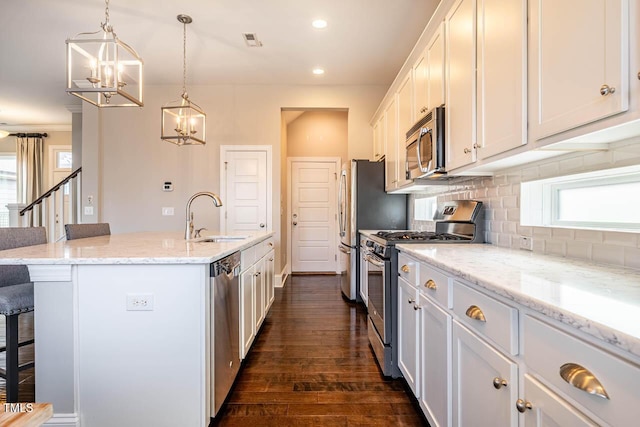 kitchen with sink, a breakfast bar area, white cabinets, stainless steel appliances, and a center island with sink