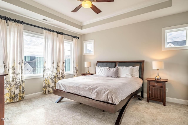 bedroom featuring crown molding, a tray ceiling, light colored carpet, and ceiling fan