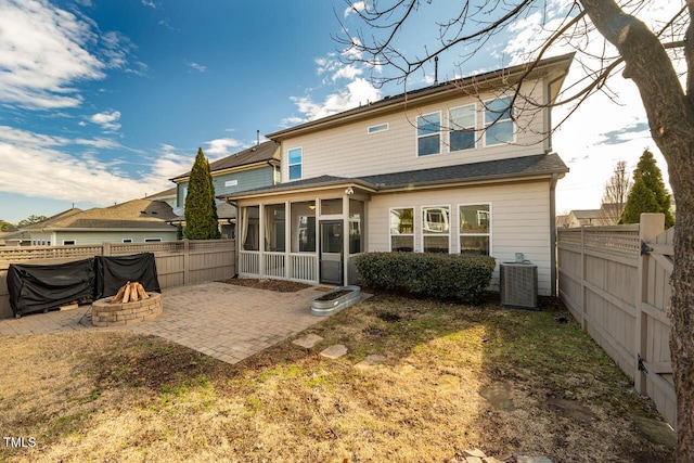 rear view of property featuring a patio, a yard, central AC unit, an outdoor fire pit, and a sunroom