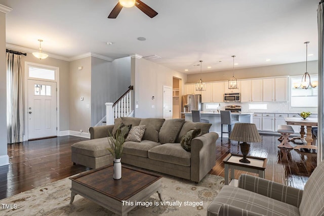 living room with ceiling fan with notable chandelier, a wealth of natural light, ornamental molding, and wood-type flooring