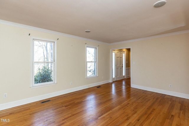 spare room with visible vents, crown molding, baseboards, and wood finished floors