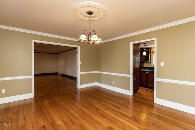 empty room with baseboards, an inviting chandelier, and wood finished floors