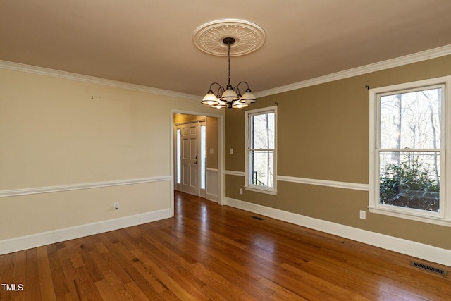 unfurnished room with a chandelier, crown molding, baseboards, and wood finished floors