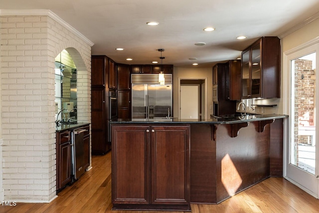 kitchen featuring a peninsula, dark countertops, light wood-type flooring, and appliances with stainless steel finishes