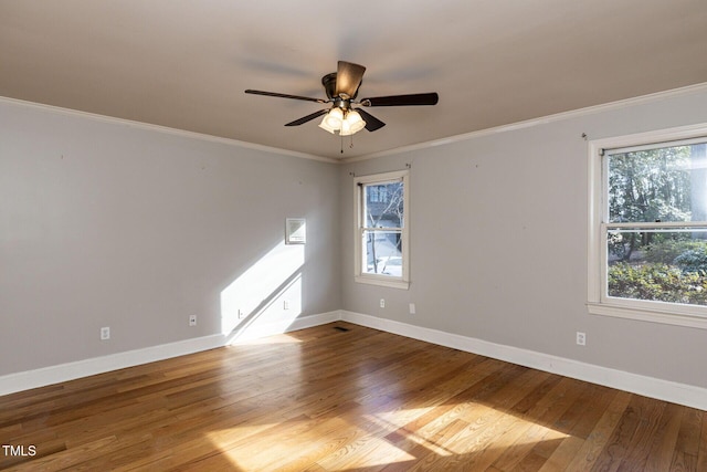 spare room with plenty of natural light, baseboards, wood-type flooring, and ornamental molding