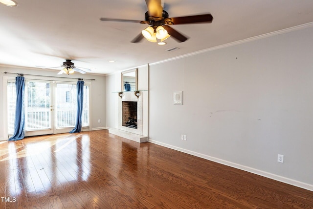 unfurnished living room featuring a fireplace with raised hearth, ceiling fan, baseboards, ornamental molding, and wood finished floors