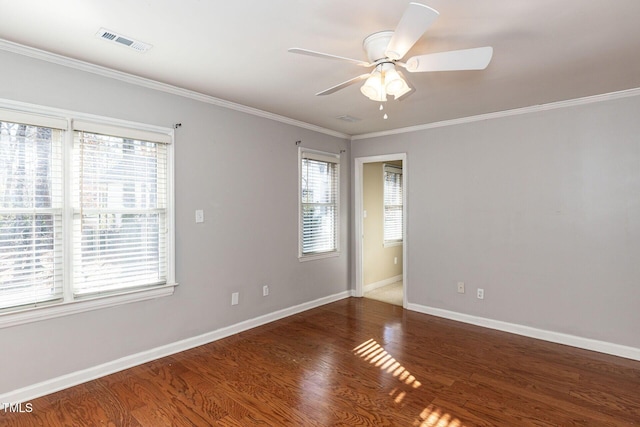 empty room with a ceiling fan, wood finished floors, visible vents, baseboards, and crown molding