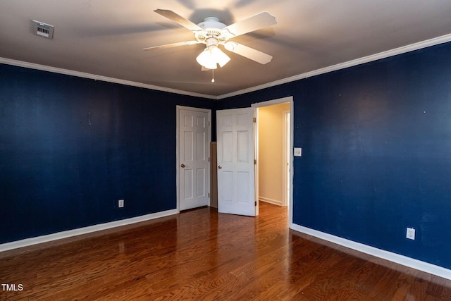 unfurnished room with visible vents, crown molding, baseboards, and wood finished floors