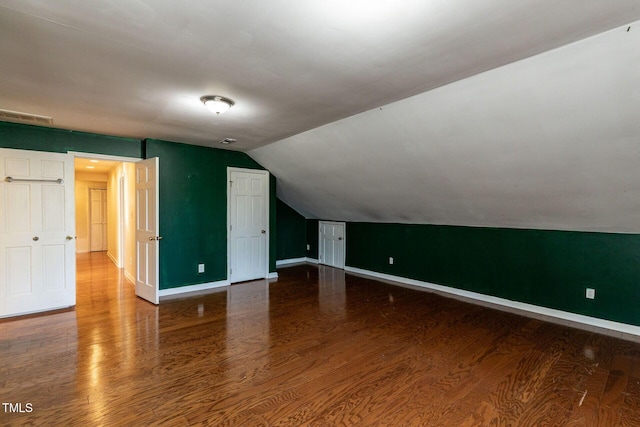 additional living space featuring visible vents, baseboards, wood finished floors, and vaulted ceiling