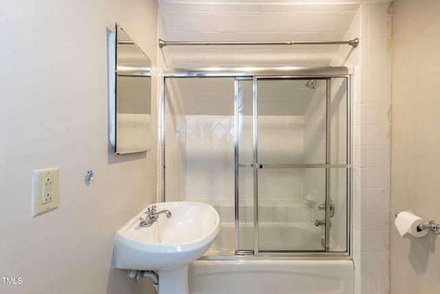 bathroom featuring combined bath / shower with glass door and a sink