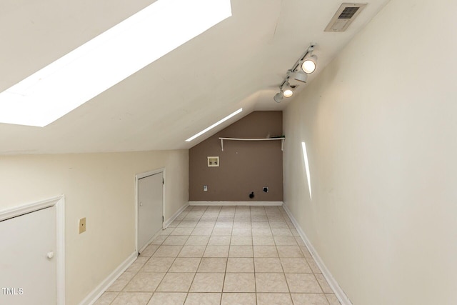 additional living space with light tile patterned flooring, visible vents, vaulted ceiling with skylight, and baseboards