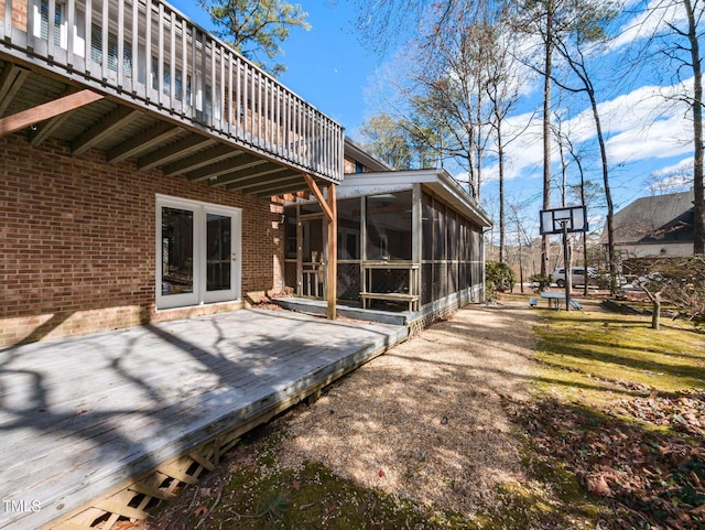 rear view of house with brick siding, a deck, and a sunroom