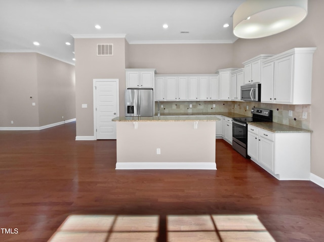 kitchen with stainless steel appliances, a towering ceiling, white cabinetry, and a center island