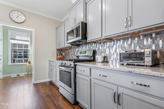 kitchen featuring stainless steel appliances, tasteful backsplash, dark hardwood / wood-style floors, light stone counters, and crown molding