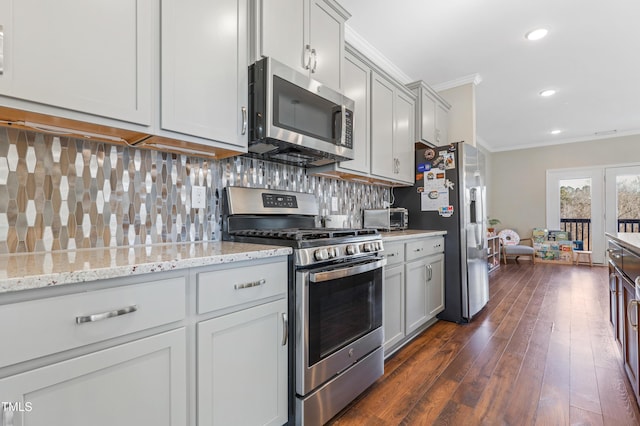 kitchen with light stone countertops, appliances with stainless steel finishes, dark hardwood / wood-style flooring, backsplash, and ornamental molding