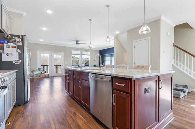 kitchen with appliances with stainless steel finishes, sink, hanging light fixtures, ceiling fan, and a center island with sink