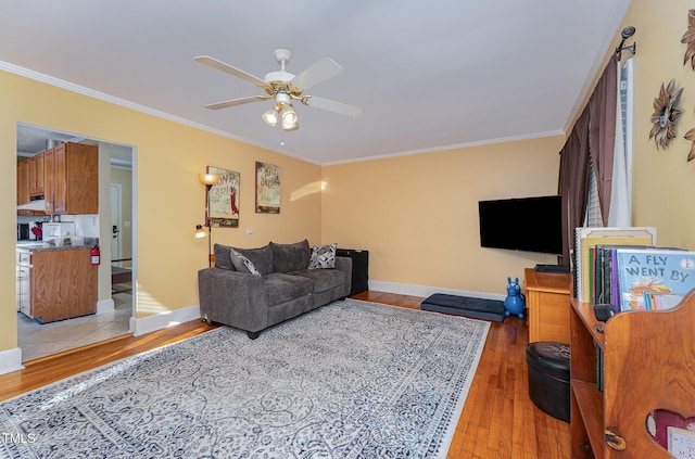 living room featuring light wood-type flooring, ceiling fan, and ornamental molding