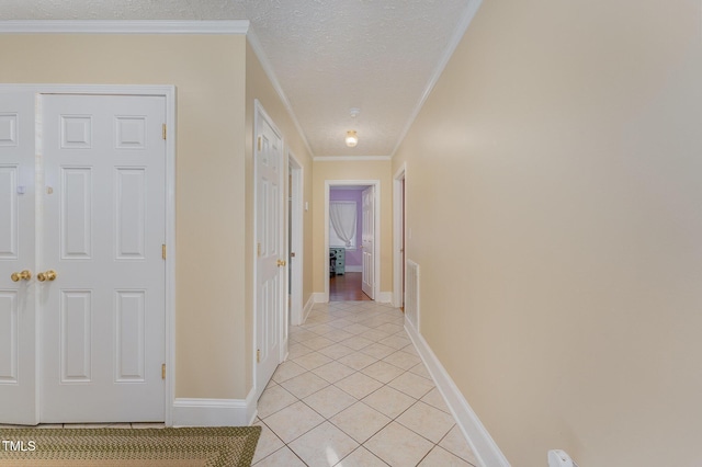 corridor featuring a textured ceiling, ornamental molding, and light tile patterned floors