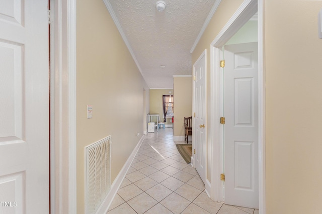 hallway with a textured ceiling, crown molding, and light tile patterned floors