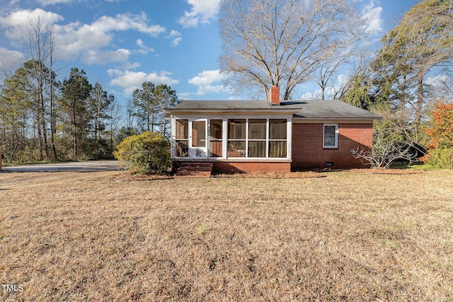 back of property featuring a sunroom and a lawn