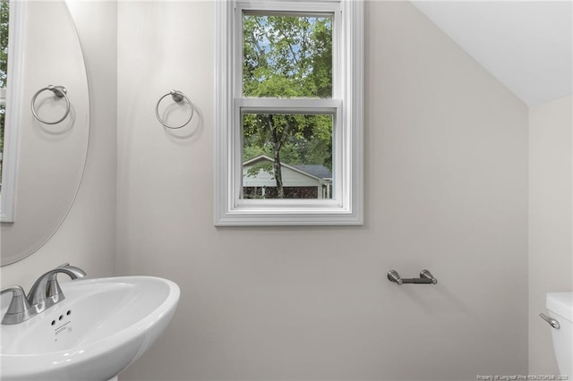 bathroom with sink, toilet, lofted ceiling, and plenty of natural light