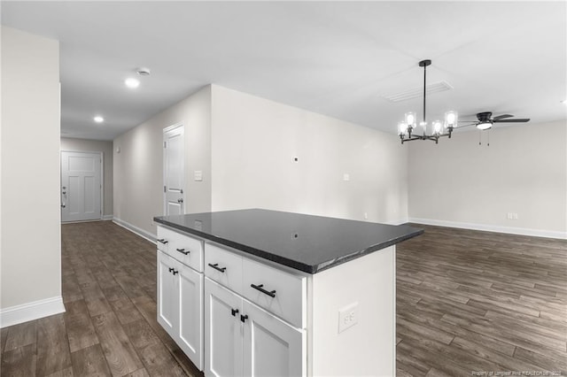 kitchen featuring a center island, dark wood-type flooring, white cabinets, decorative light fixtures, and ceiling fan with notable chandelier