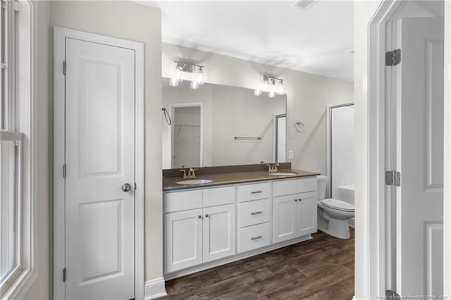 bathroom with walk in shower, toilet, vanity, and wood-type flooring