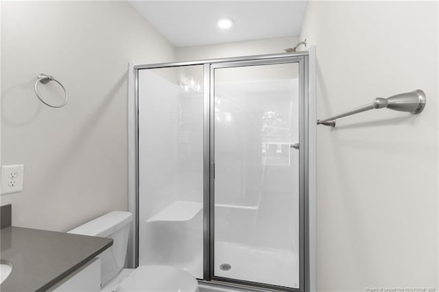 bathroom with an enclosed shower, vanity, and toilet