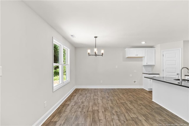 kitchen featuring sink, white cabinets, hanging light fixtures, dark hardwood / wood-style flooring, and a chandelier