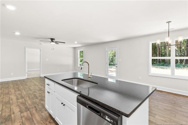 kitchen with stainless steel dishwasher, hanging light fixtures, a center island with sink, white cabinets, and sink