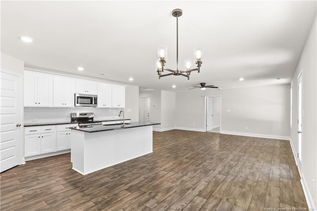 kitchen with appliances with stainless steel finishes, ceiling fan with notable chandelier, white cabinets, decorative light fixtures, and sink