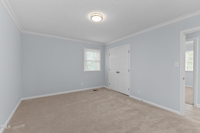 empty room featuring crown molding, light colored carpet, and plenty of natural light