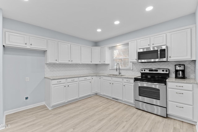 kitchen with sink, stainless steel appliances, white cabinets, and light stone countertops